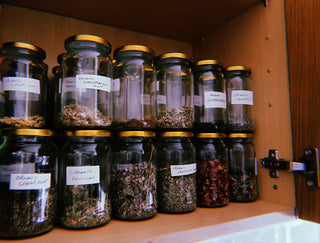 Collection of glass jars with labels on a wooden shelf