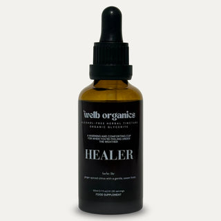 Brown glass bottle with dropper labeled 'welb organics HEALER' on a neutral background