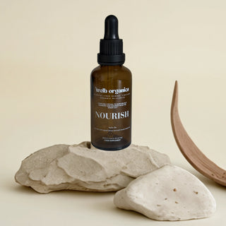 Glycerite dropper bottle labeled 'Nourish' on a stone surface with a neutral background