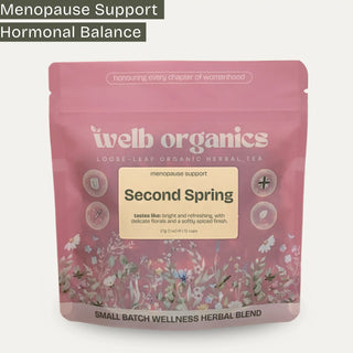 A pink stand-up pouch of Welb Organics Second Spring loose-leaf herbal tea, featuring floral illustrations and text highlighting menopause support and hormonal balance, on a light gray background.