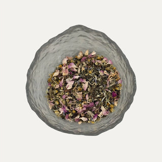 Glass container with dried herbs and flowers on a light grey background