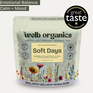 A stand-up pouch of Welb Organics Soft Days loose-leaf herbal tea on a light gray background, with a black circular 'great taste 2026' badge at the top right and a text banner at the top left reading 'Emotional Balance Calm + Mood'. The package is mostly off-white with a cream label, dark green brand text, and multicolored floral illustrations along the bottom.