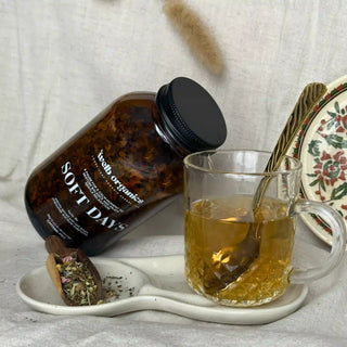 Bottle labeled 'Soft Days' next to a glass of tea on a tray with a spoon.